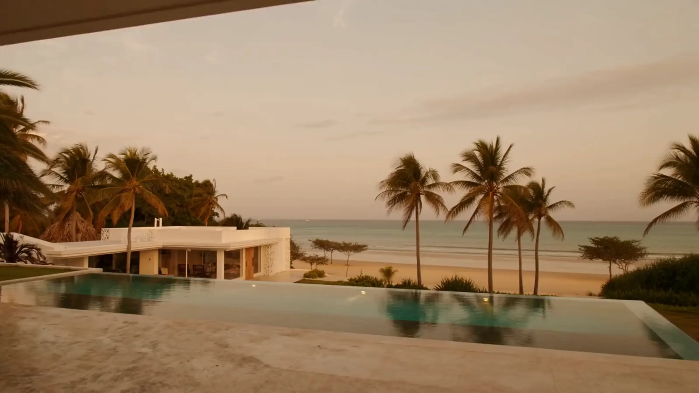 A modern villa with an infinity pool facing the sea at sunset